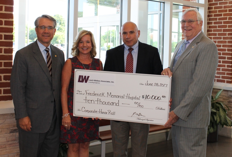 four people holding a large check